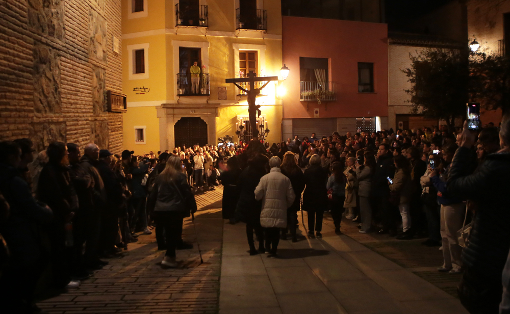 Un turista contempla desde la ventana de su habitación la salida del Cristo de la Expiración de Santo Domingo el Antiguo, que congregó a mucho público a las tres de la mañana.