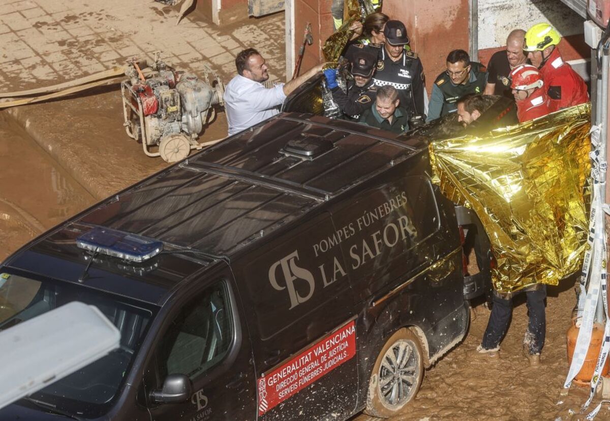 Un furgón de la funeraria sale de un garaje con cadáveres localizados tras el paso de la DANA, en la pedanía de la Torre, en València  / ROBER SOLSONA